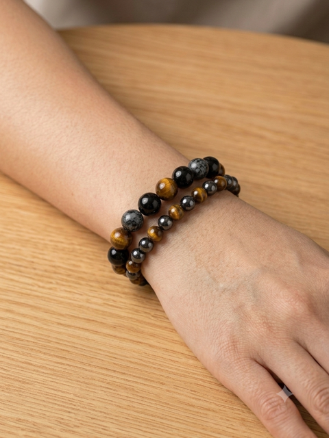 Set de deux bracelets œil de tigre et pierres noires portés sur un poignet