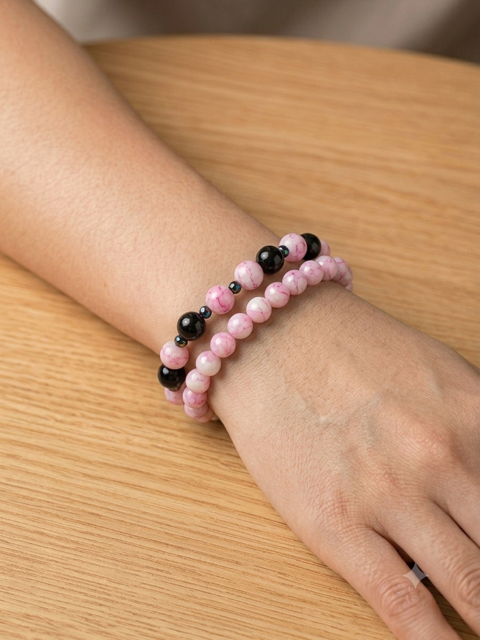 Set de deux bracelets perles rose et noires portés sur un poignet