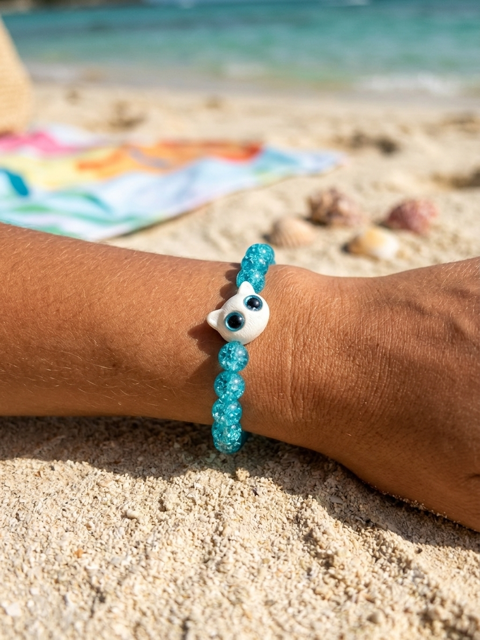 Bracelet œil turquoise porté sur un poignet à la plage